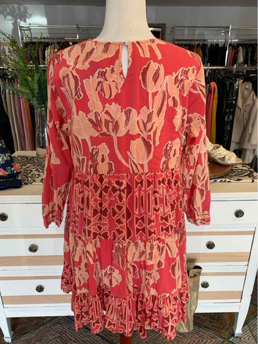 Coral pink floral dress with tiered ruffle skirt and long sleeves, featuring a fitted waist panel.