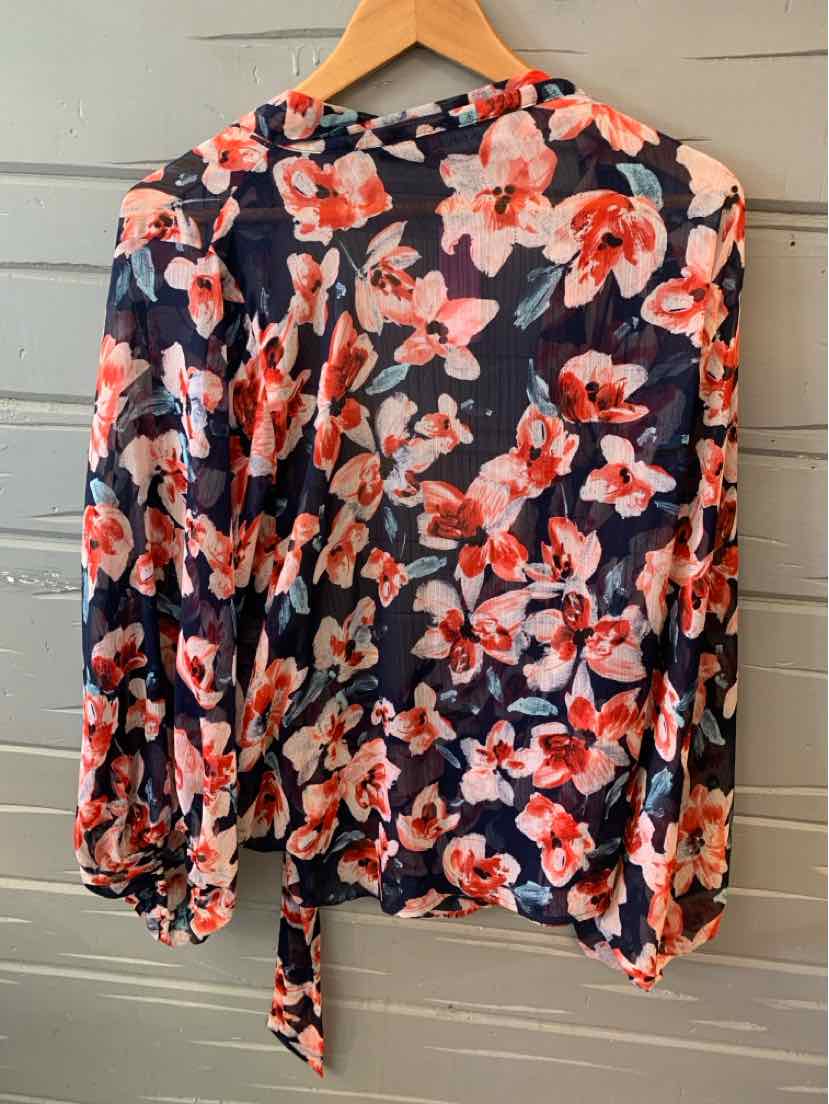 Navy blue blouse with vibrant pink and white floral print, long sleeves, tie detail at hem.