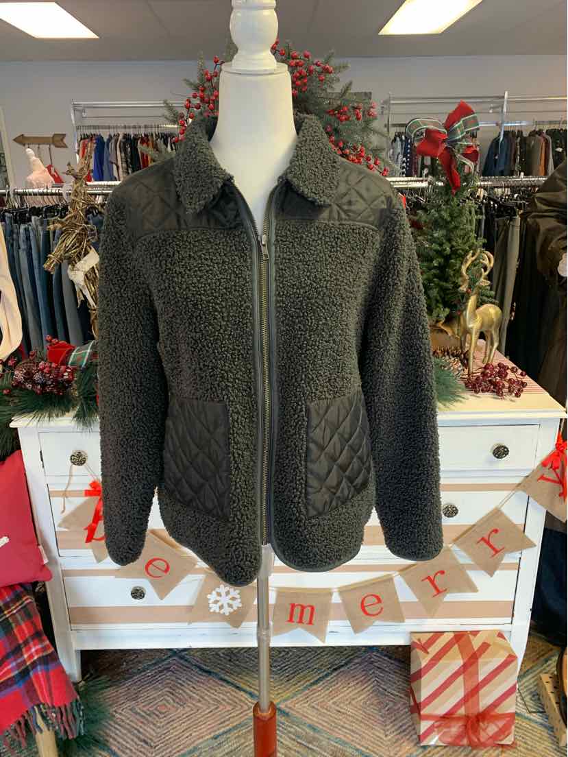 Black quilted jacket with collar and zip front on white mannequin in holiday store setting.