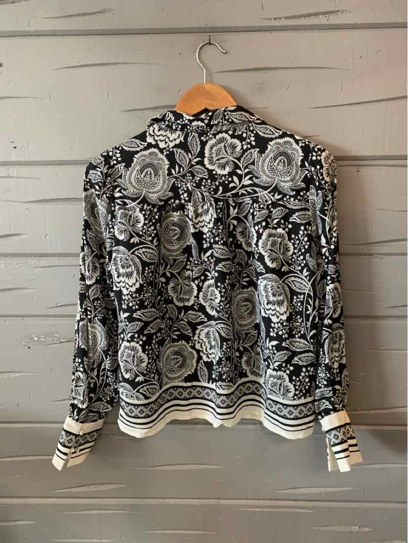 Black long-sleeve blouse with white and gray rose floral pattern, buttoned cuffs, and striped hem trim.