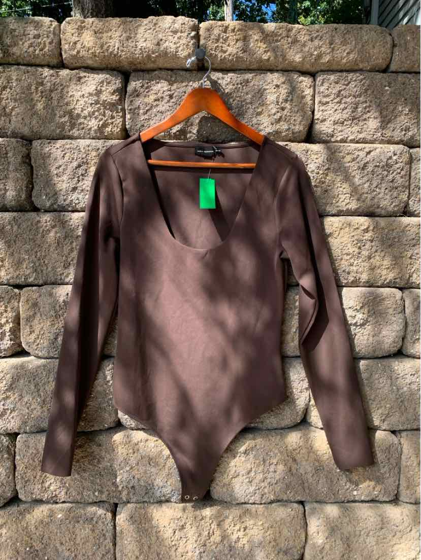 Long-sleeve solid dark brown bodysuit with scoop neckline on wooden hanger against stone wall background.