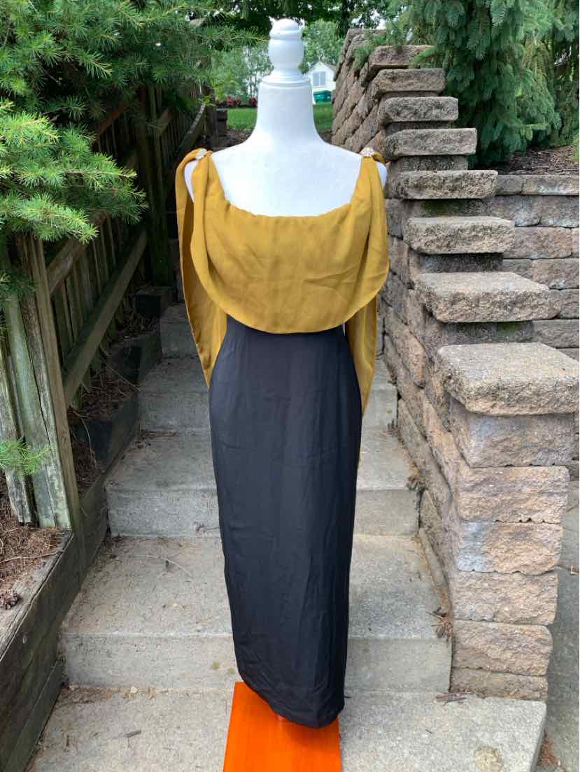 Black midi dress with fitted silhouette and mustard yellow draped off-shoulder overlay.