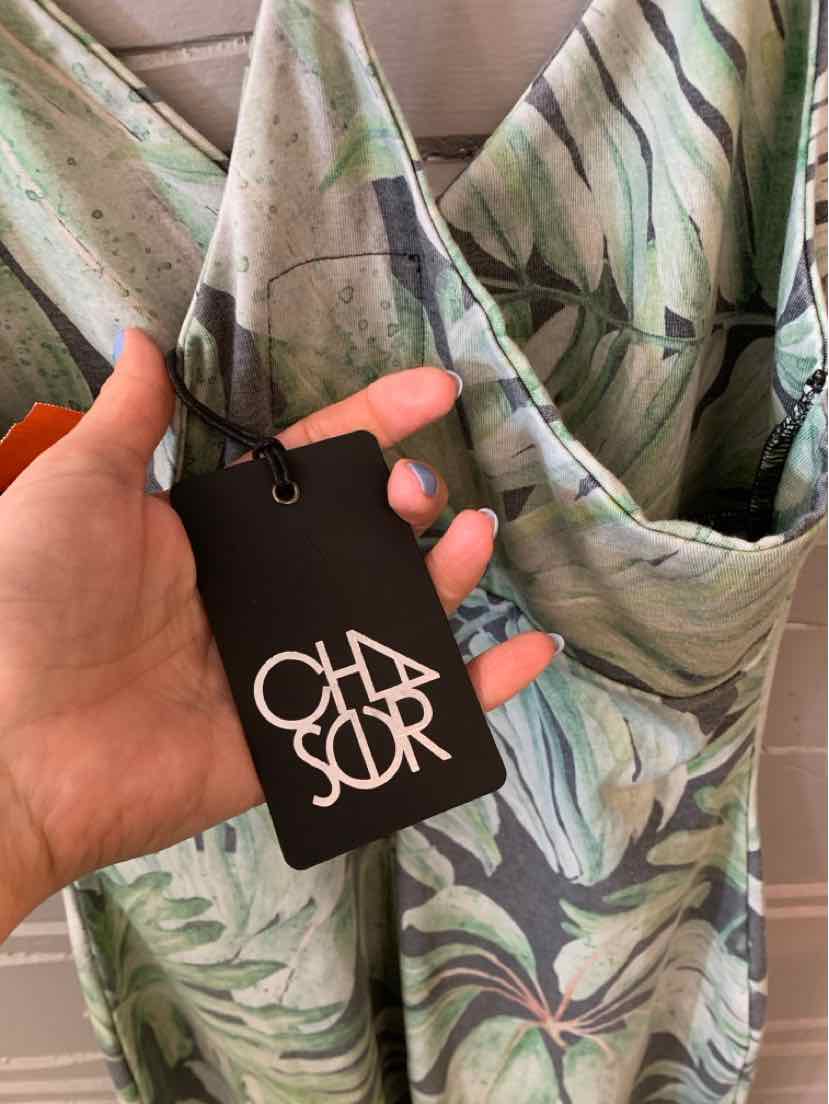 Green tropical print fabric with draped neckline on a small garment and black CHA SOR tag.