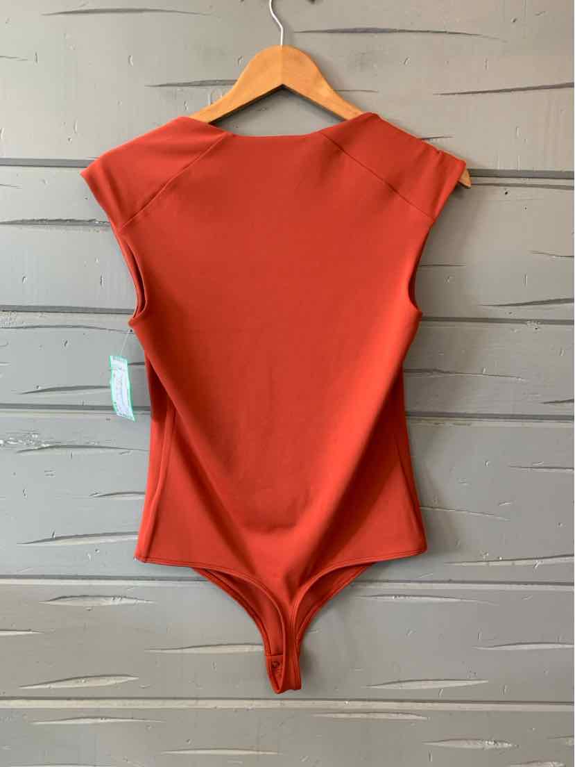 Rust-orange sleeveless bodysuit with a scoop neckline and smooth fabric hanging on wooden hanger.