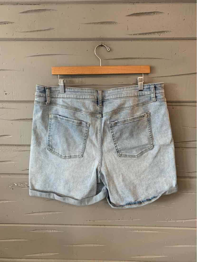 Light blue denim shorts with rolled hems and back patch pockets hanging on wooden hanger.