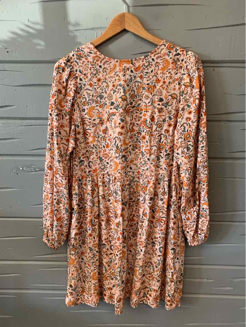 Long-sleeve floral dress in peach with gathered waist and buttoned front lace-up neckline.