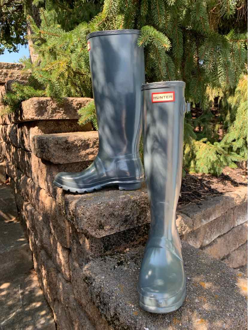 Gray glossy rubber rain boots with a mid-calf height and a rectangular red and white Hunter logo on the front upper shaft.