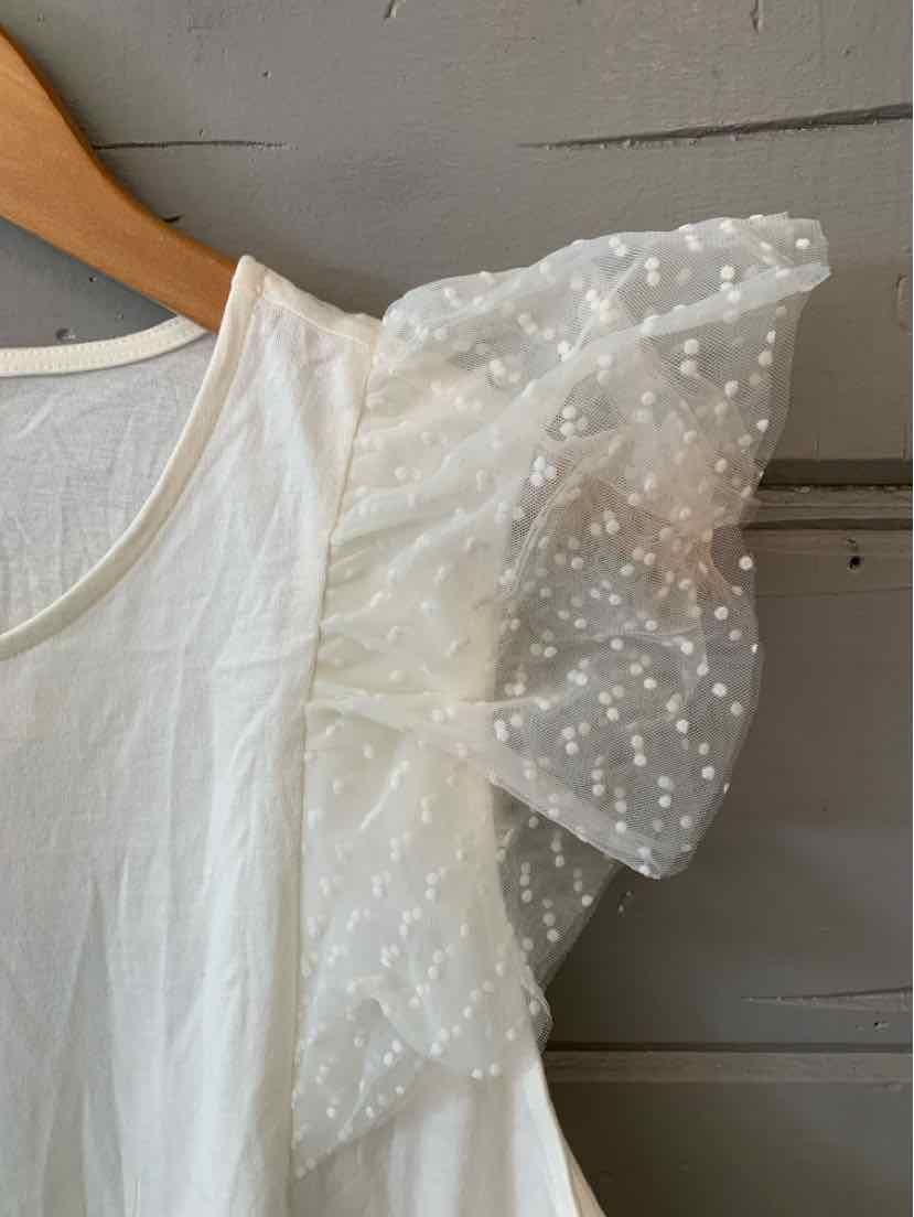 White blouse with sheer puff sleeve featuring polka dot texture and a round neckline.