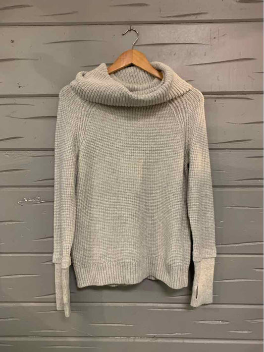 Light gray knit sweater with wide cowl neck and long ribbed cuffs hanging on wooden hanger.