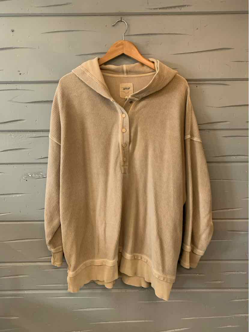 Tan oversized zip-up hoodie with long sleeves and ribbed cuffs on wooden hanger.