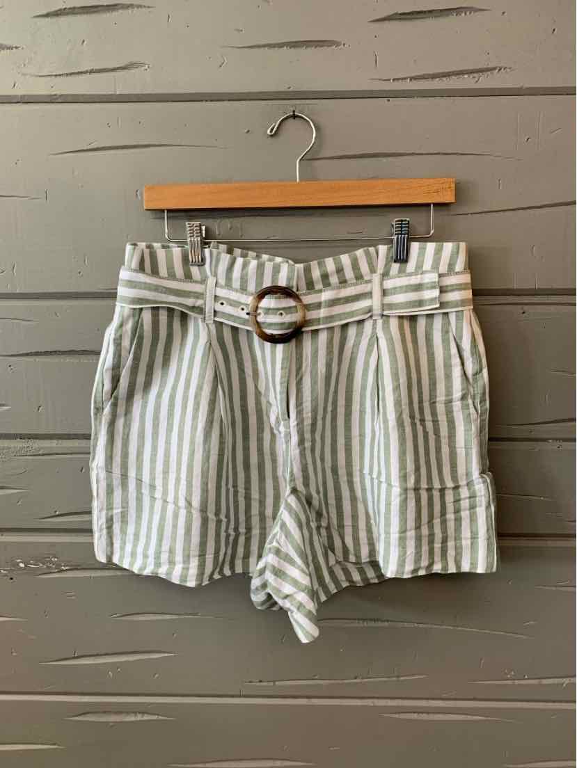 High-waisted white shorts with vertical green stripes, a fabric belt with a round buckle, and front pockets.