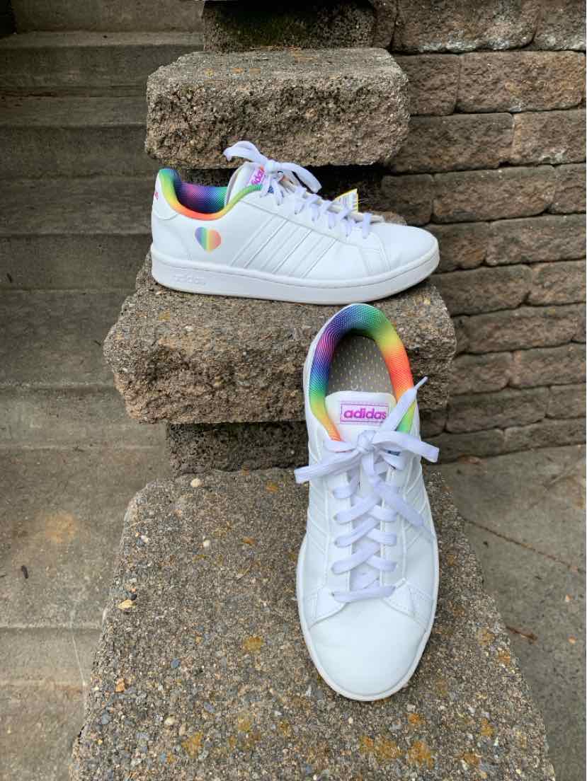 White low-top Adidas sneakers with rainbow accents on heel and collar, size 8.
