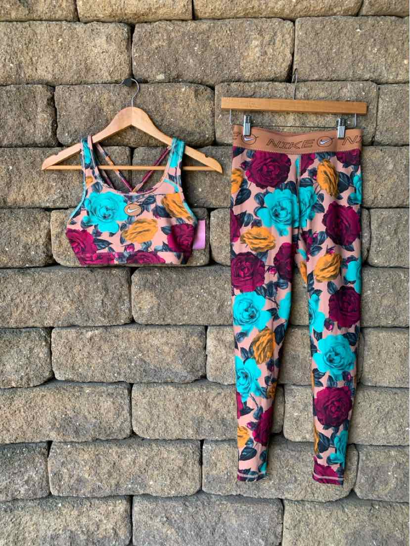 Floral-print sports bra and leggings set with vibrant blue, purple, and orange flowers on a beige background.