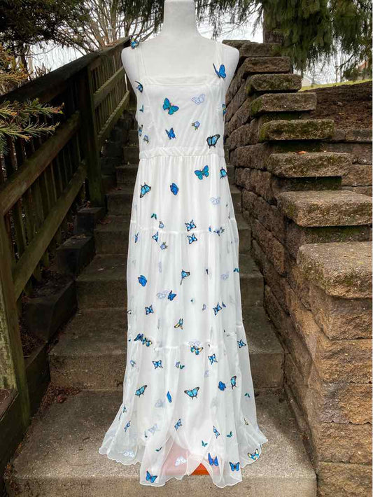 White sleeveless maxi dress with blue butterfly print and tiered skirt.