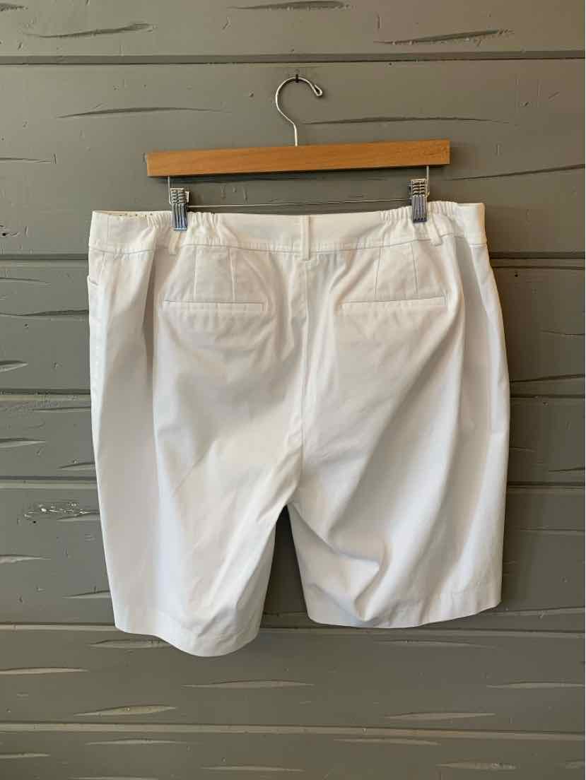 White knee-length shorts with folded hems and back pockets, displayed on wooden hanger.