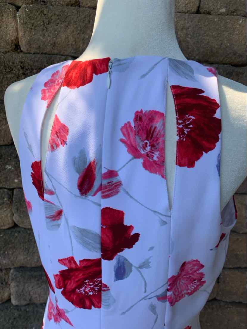 White sleeveless dress with large red and pink floral print on lightweight fabric.