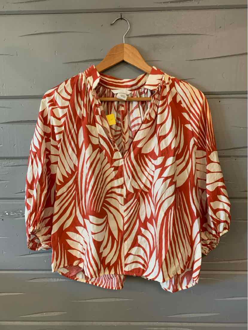 Lightweight blouse with vibrant orange and white tropical leaf print, long sleeves, round neckline, and front tassel ties.