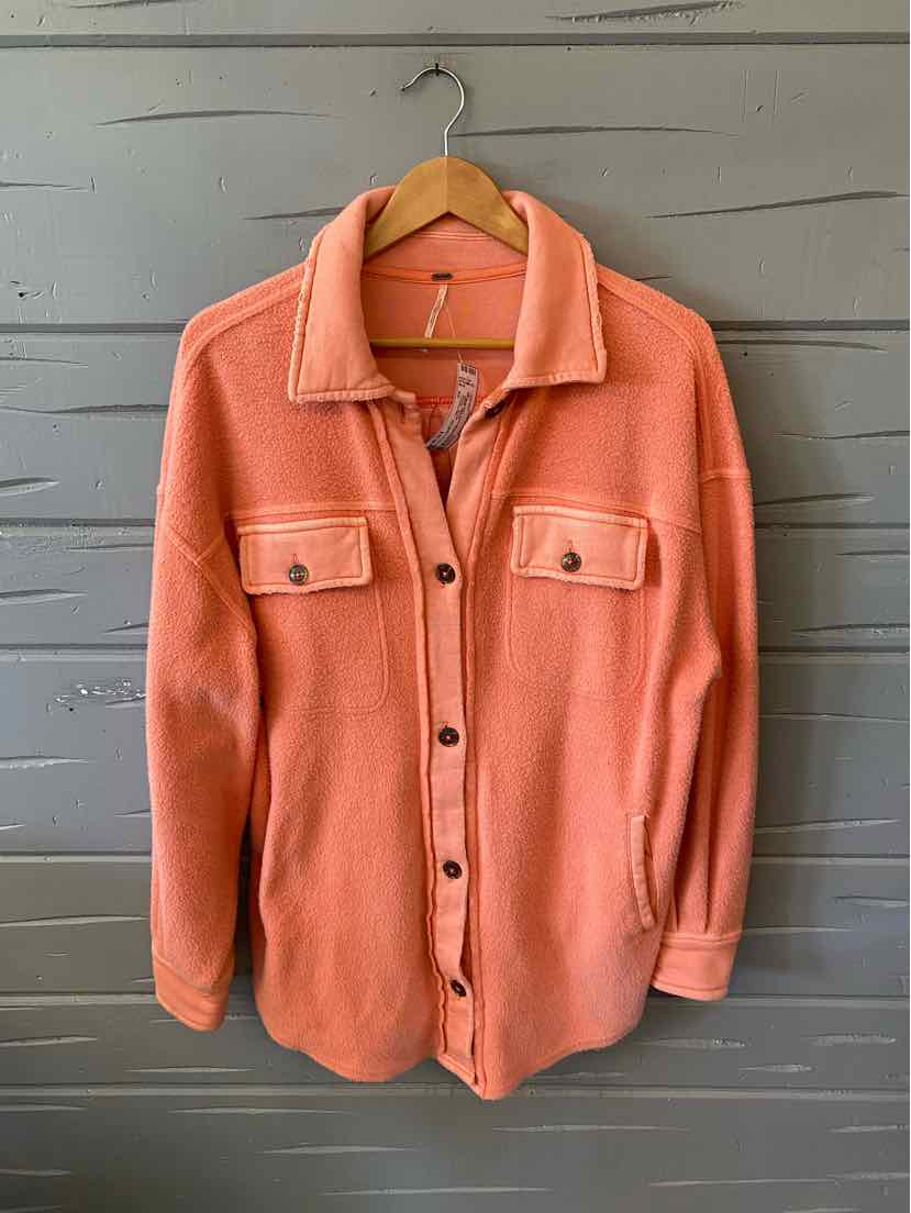 Coral button-up shirt jacket with flap chest pockets and long sleeves on wooden hanger.
