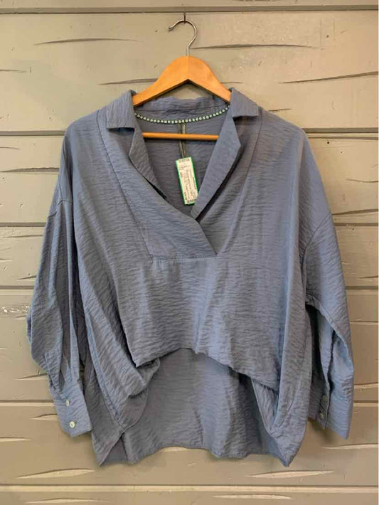 Blue-gray oversized blouse with textured fabric, wide collar, and buttoned cuffs.