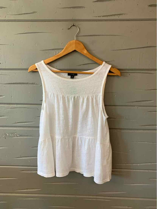 White sleeveless cotton tank top with a relaxed fit and tiered hem on a wooden hanger.