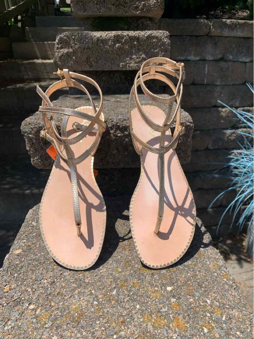 Tan leather open-toe sandals with thin ankle straps and a small buckle closure, flat sole.