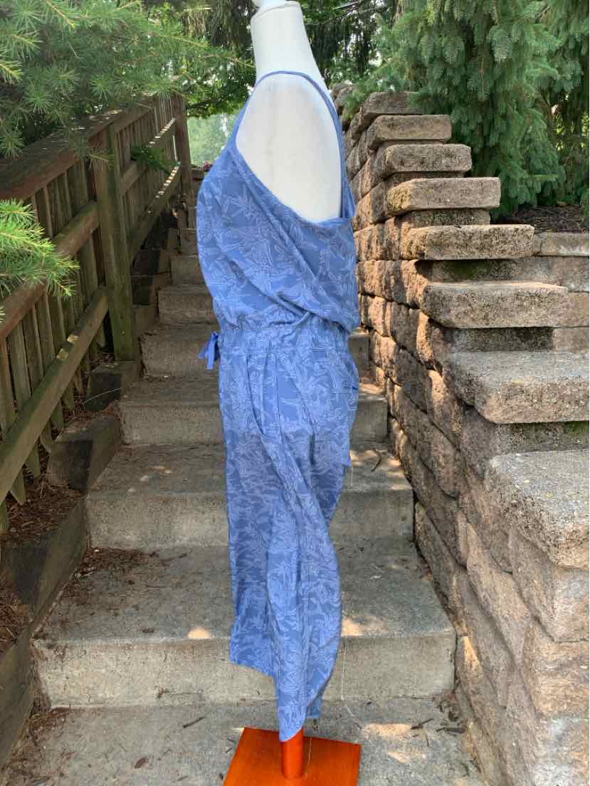 Blue sleeveless patterned jumpsuit with cinched waist and relaxed fit on white mannequin.