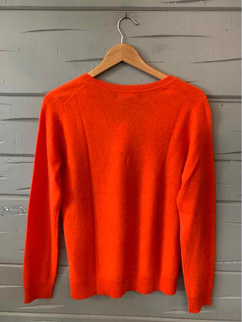 Bright orange long-sleeve cashmere sweater with a crew neckline, displayed on wooden hanger.