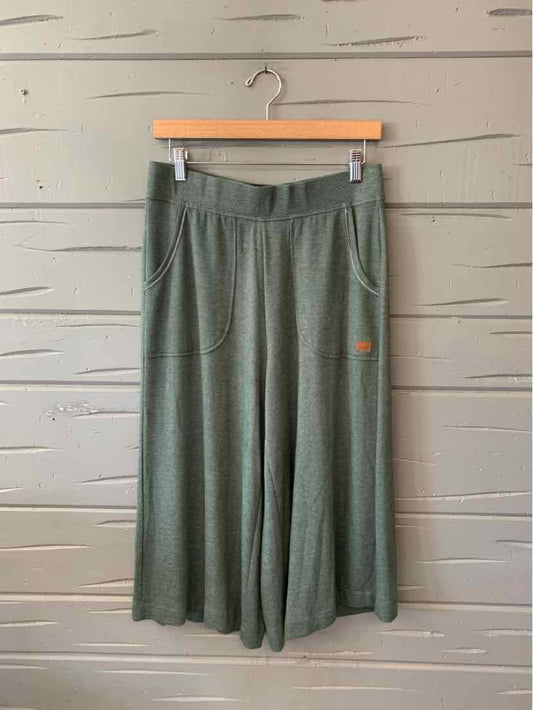 Olive green wide-leg pants with an elastic waistband and side pockets, small orange logo on pocket.