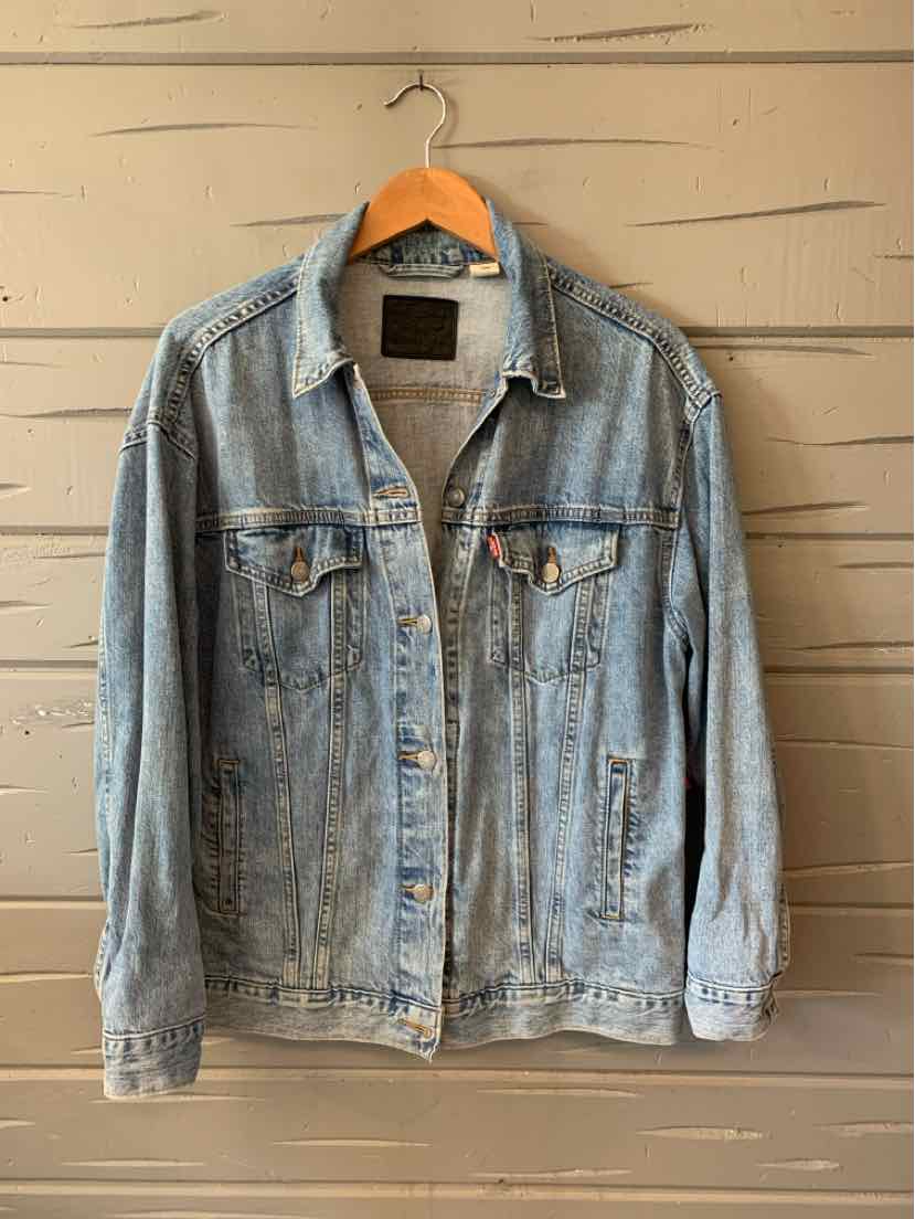 Light blue denim Levi's jacket with button front and chest pockets hanging on wooden hanger.