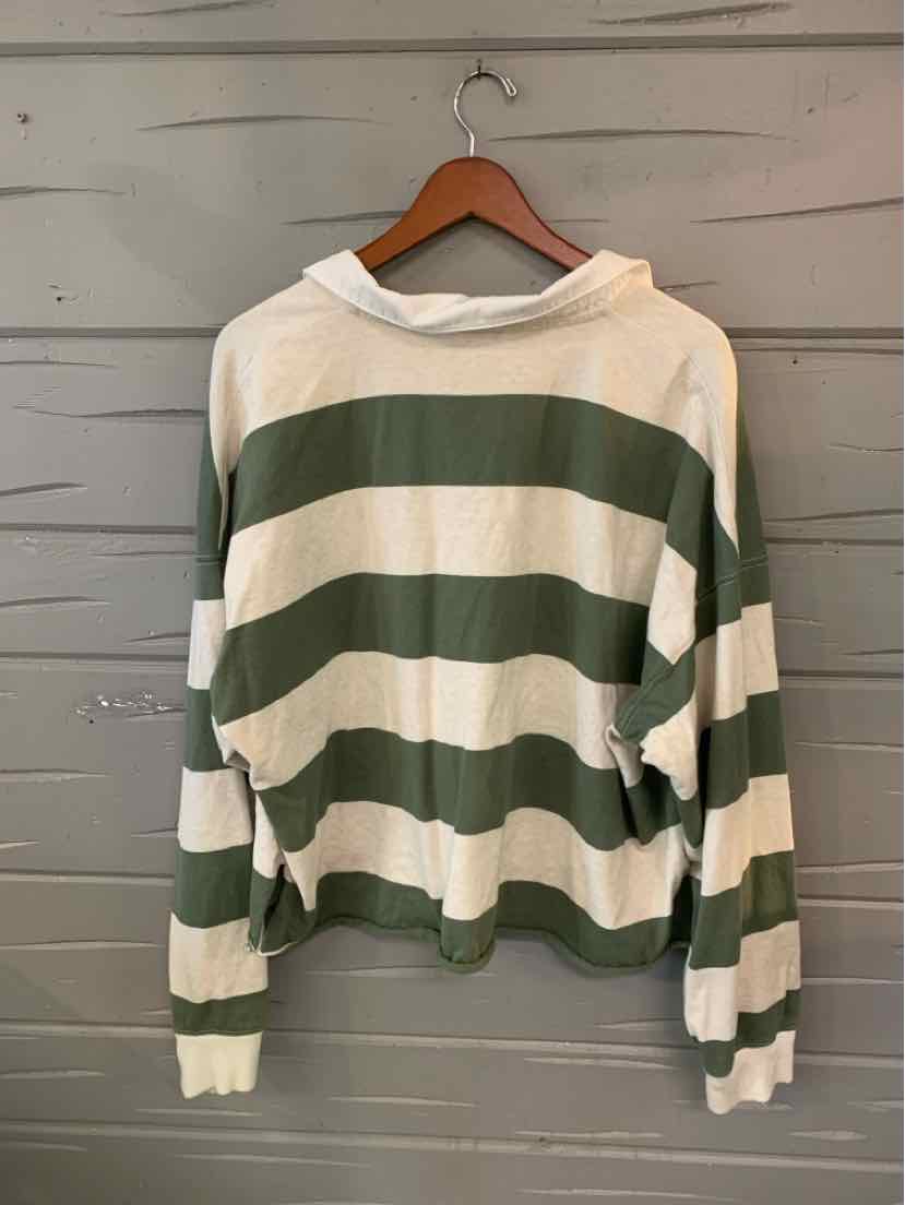 Long-sleeve cropped shirt with wide horizontal green and white stripes, ribbed cuffs, and relaxed fit on wooden hanger.