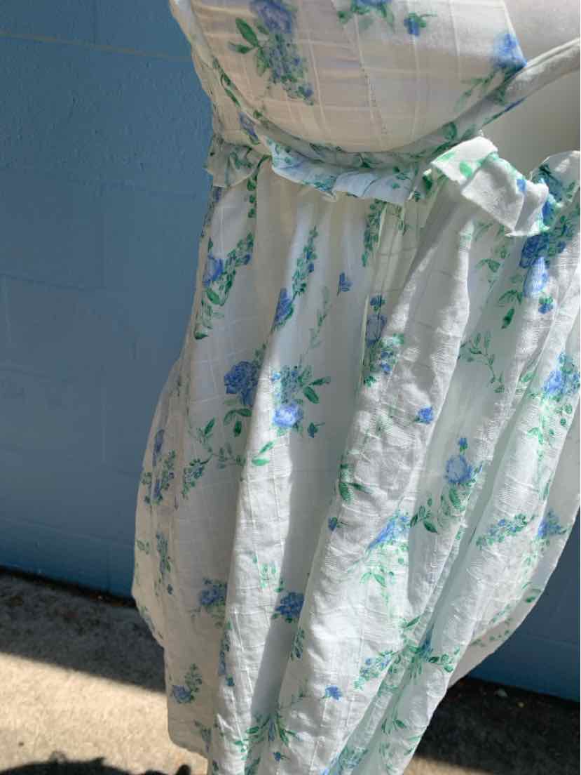 White floral dress with blue and green flowers, cinched waist, and short puff sleeves.