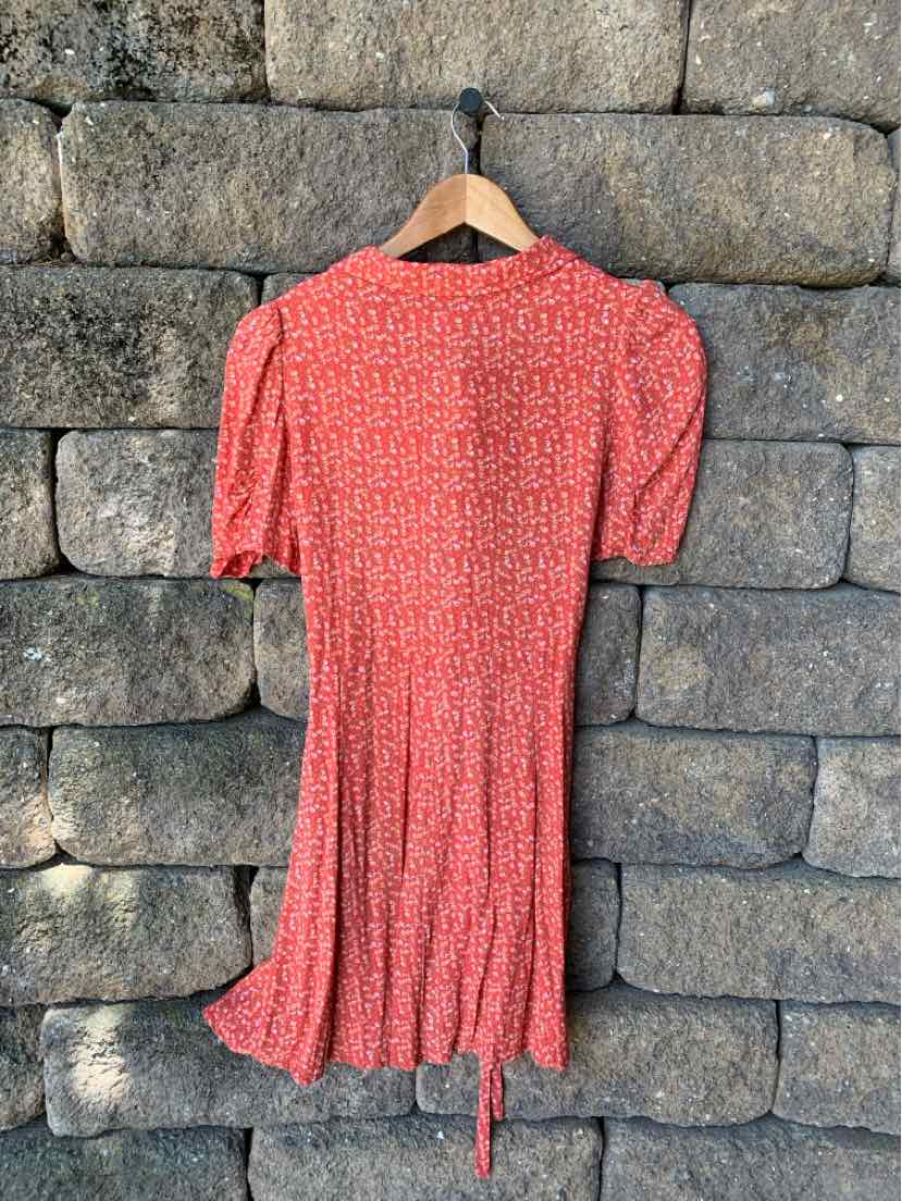 Red floral knee-length dress with short puff sleeves and tie waist detail.
