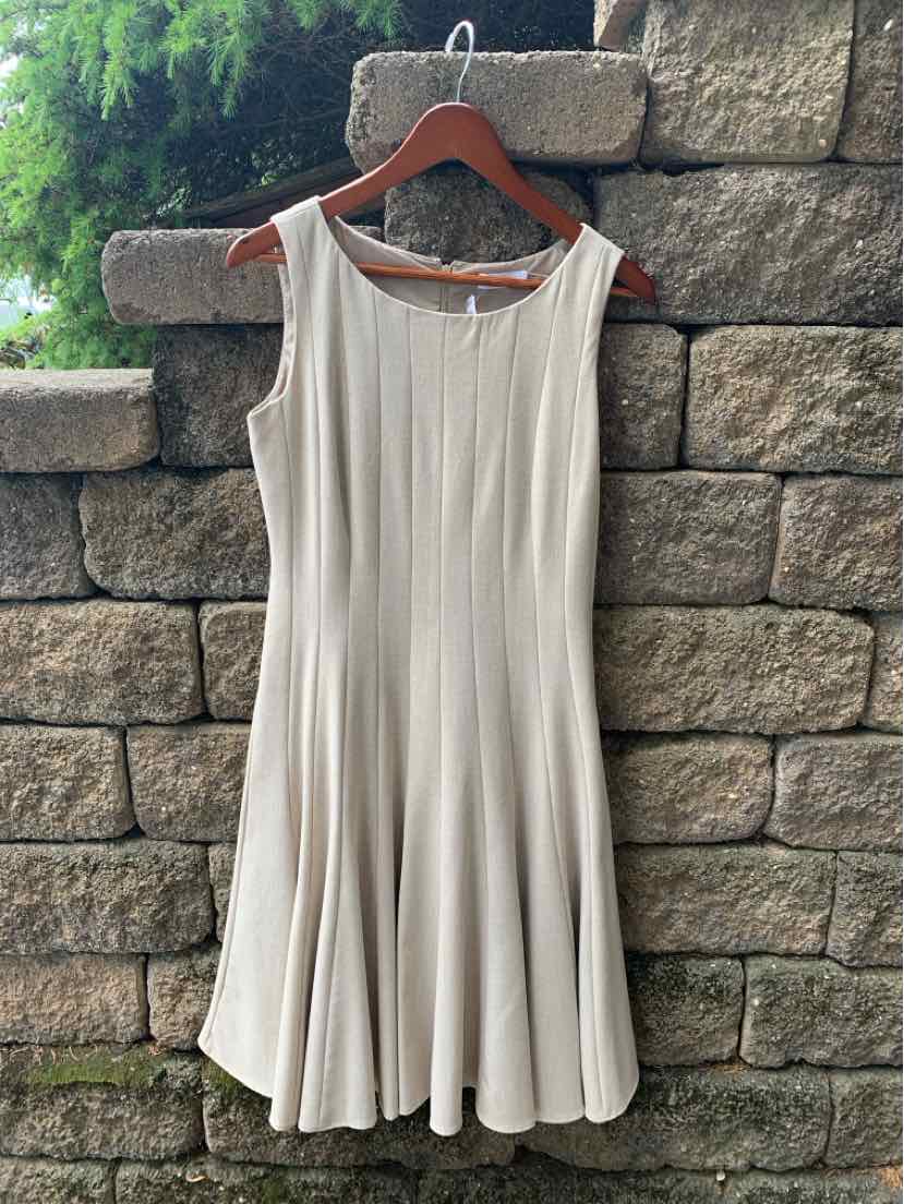 Beige sleeveless Calvin Klein dress with pleated skirt, size 4, hanging on wooden hanger.