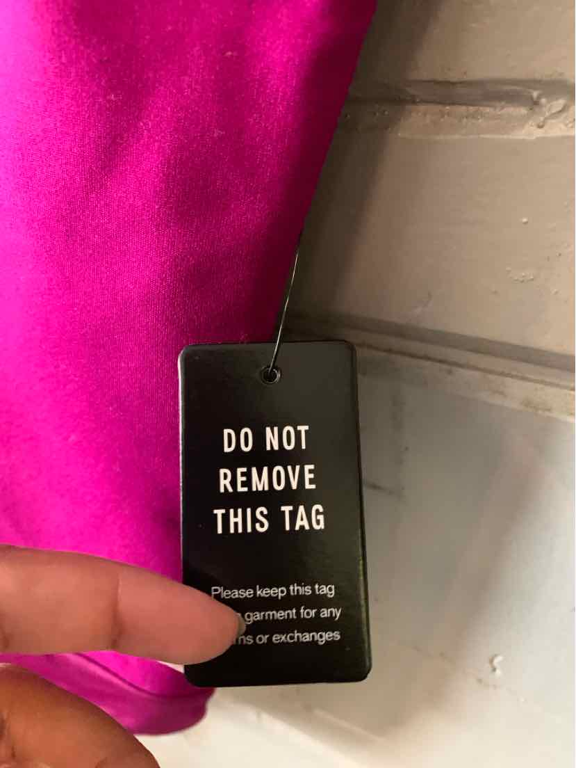 Bright fuchsia fabric with a black hanging tag reading "Do Not Remove This Tag" in white text.