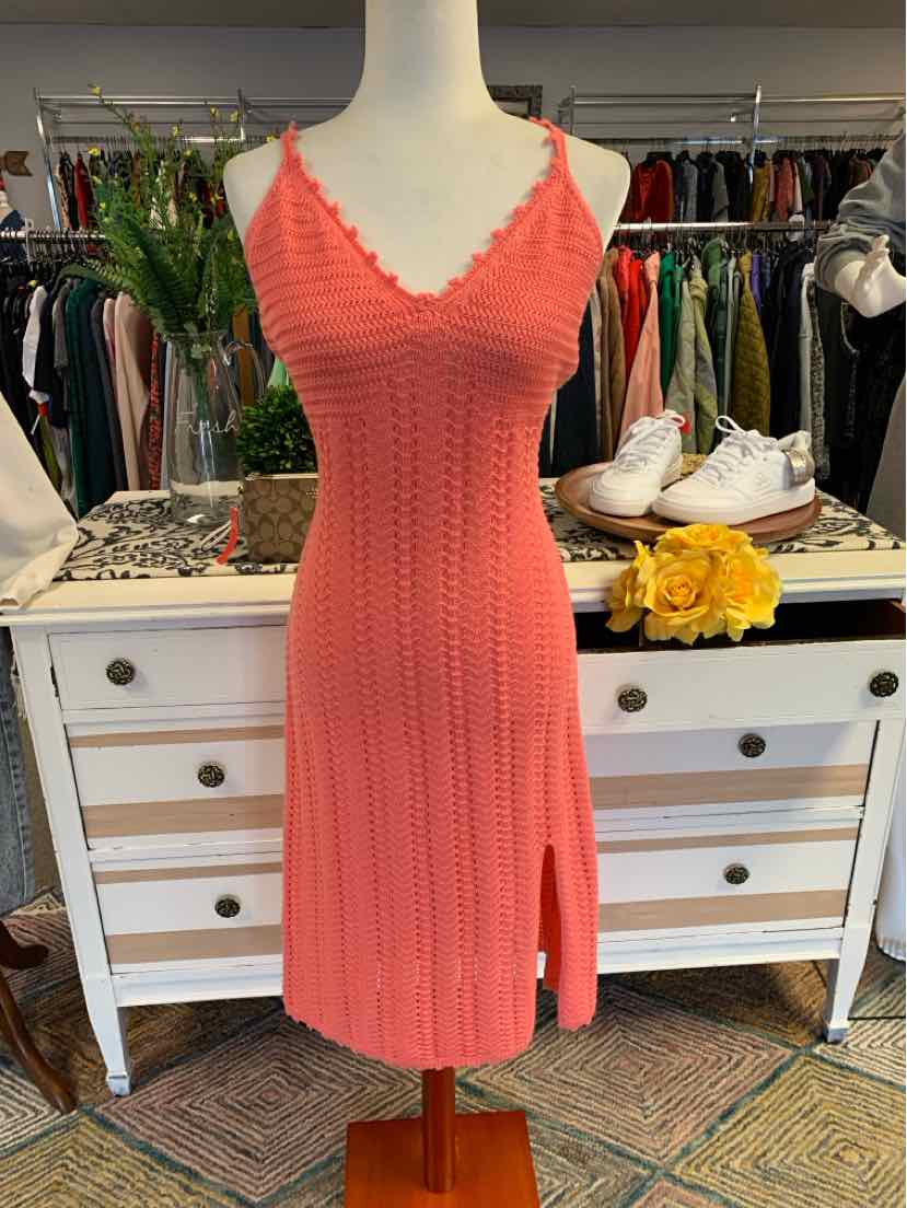 Coral pink knit sleeveless dress with V-neck and side slit on mannequin.