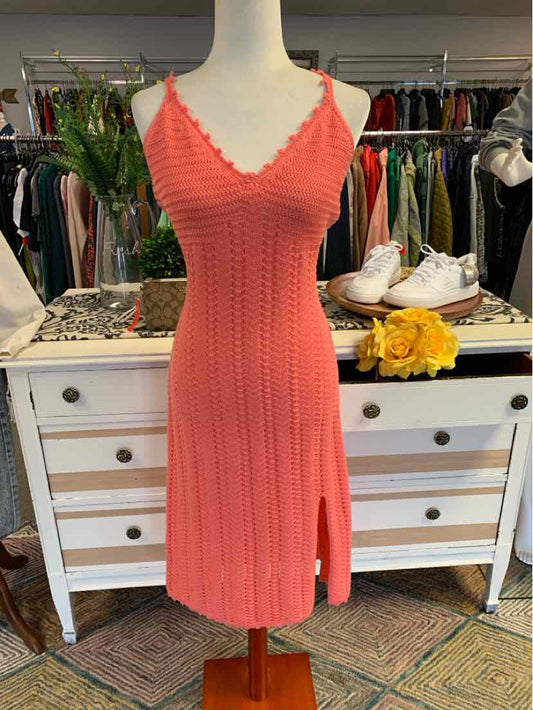 Coral pink knit sleeveless dress with V-neck and side slit on mannequin.
