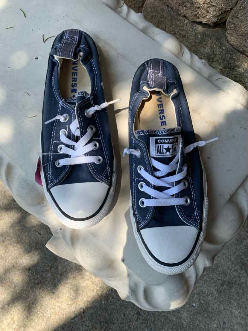 Pair of navy blue low-top Converse sneakers with white rubber toe caps and white laces, size 9.