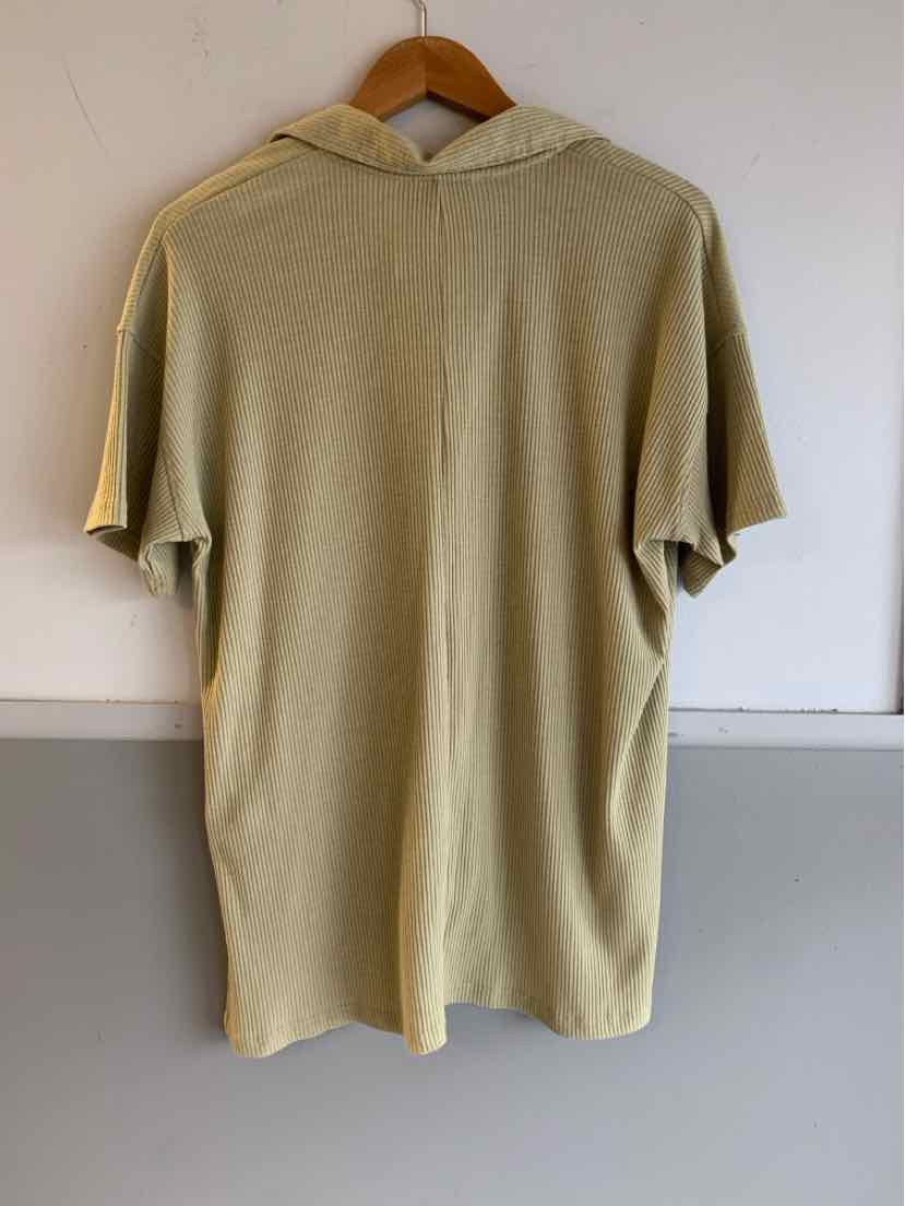Light green short-sleeve hoodie with relaxed fit hanging on wooden hanger against plain wall.