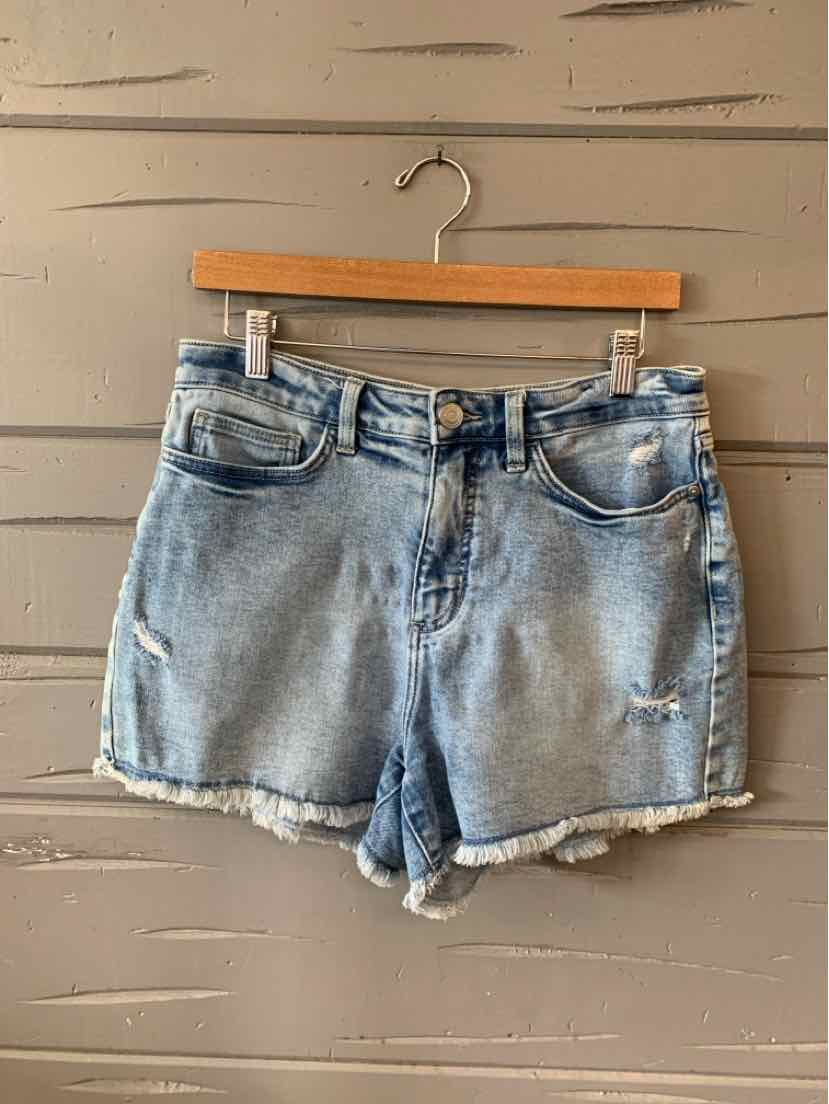 Light blue denim shorts with frayed hems and front pockets hanging on wooden hanger.