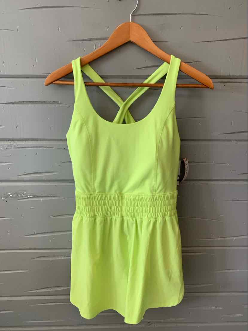 Light green sleeveless romper with a fitted waist and crisscross back straps on a wooden hanger.