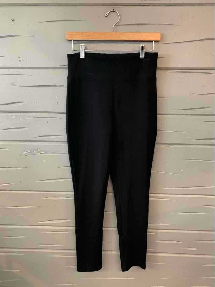 Black high-waisted slim-fit women's pants with ankle-length cut hanging on wooden hanger.