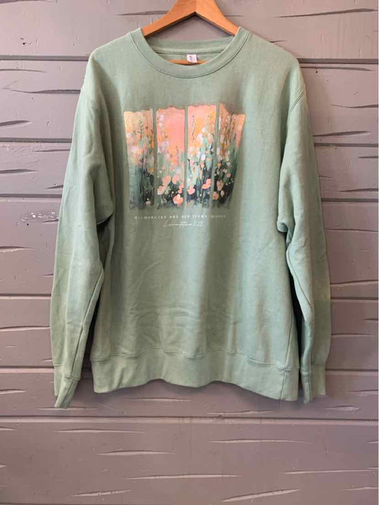 Sage green long-sleeve T-shirt with a colorful floral graphic and “Love in Faith” text.