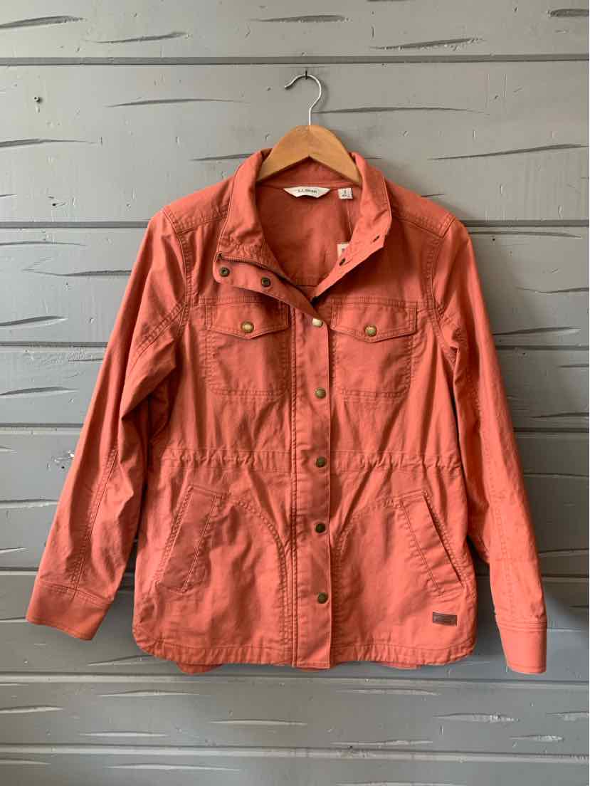 Rust-colored lightweight cotton jacket with snap buttons and two chest pockets on wooden hanger.