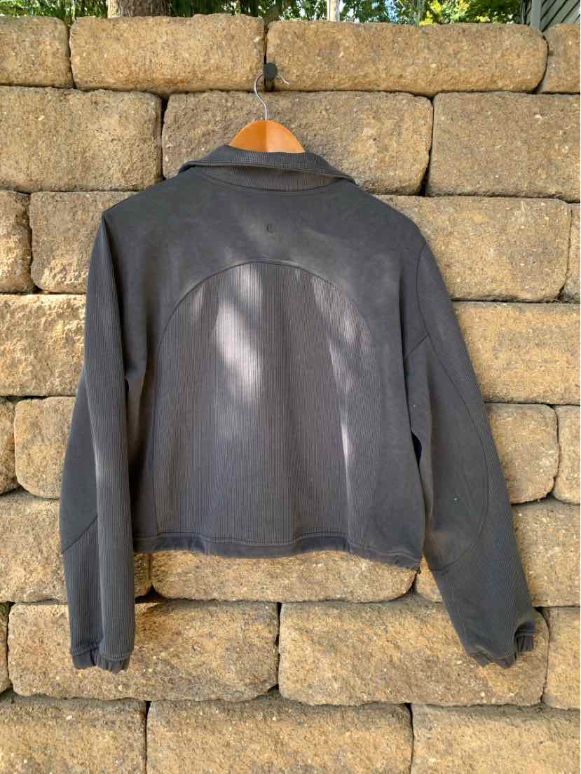 Dark gray long-sleeve athletic jacket with a high collar and curved seam details on the back.