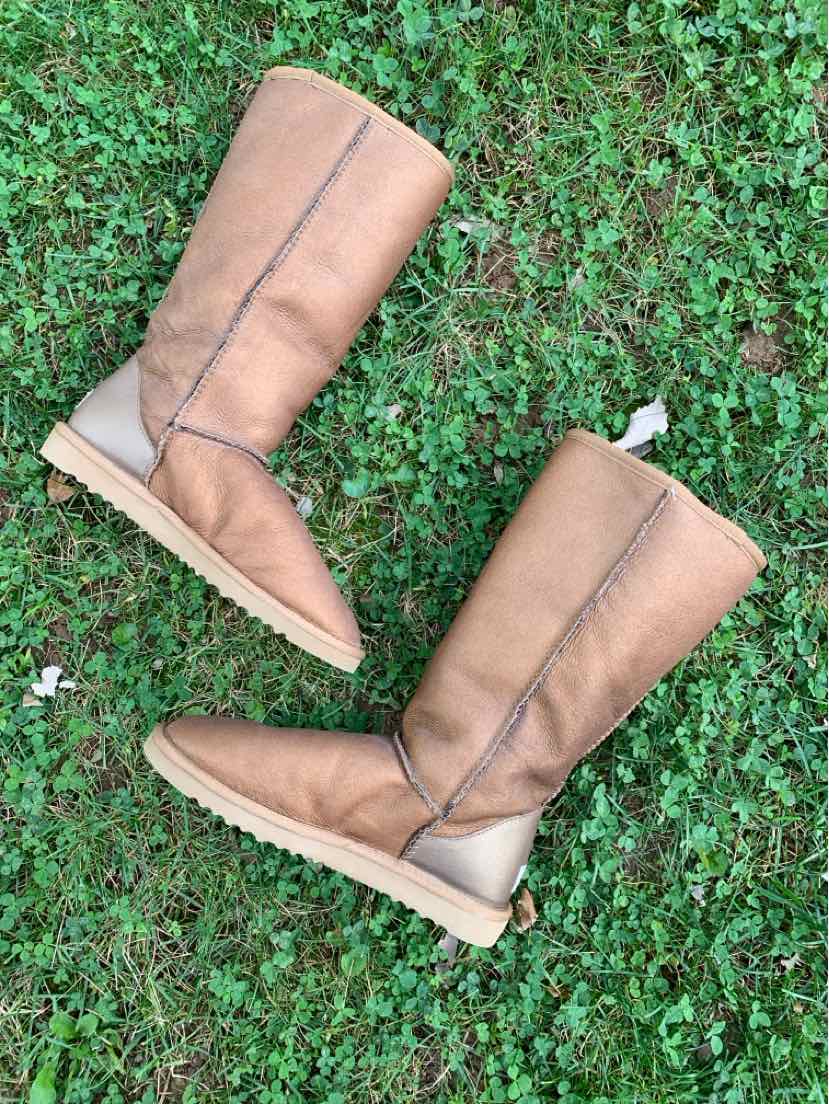 Pair of tan suede knee-high boots with shearling lining, rounded toes, and flat soles.