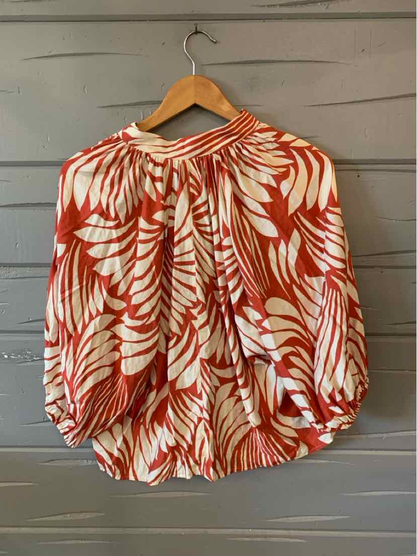 Women's tropical print blouse in rust orange and white with long puff sleeves and gathered neckline.