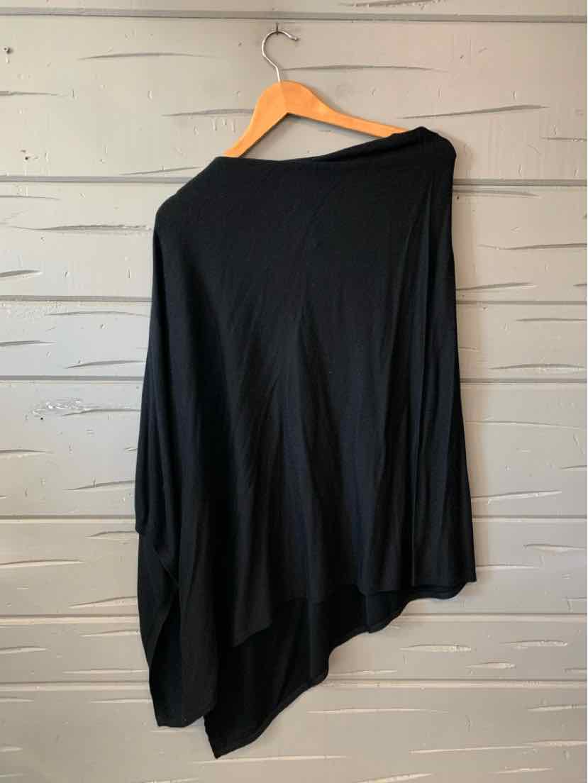 Black asymmetrical poncho-style sweater with long sleeves, draped fit, hanging on wooden hanger.