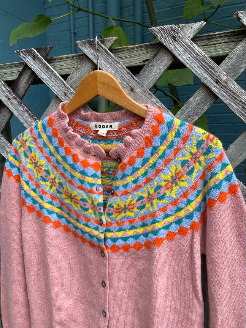Pink sweater with multicolored geometric yoke pattern and small buttons down front.
