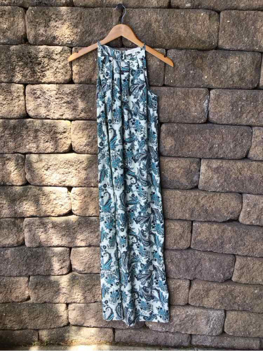 Blue and white sleeveless paisley maxi dress with gathered waist on wooden hanger against stone wall.