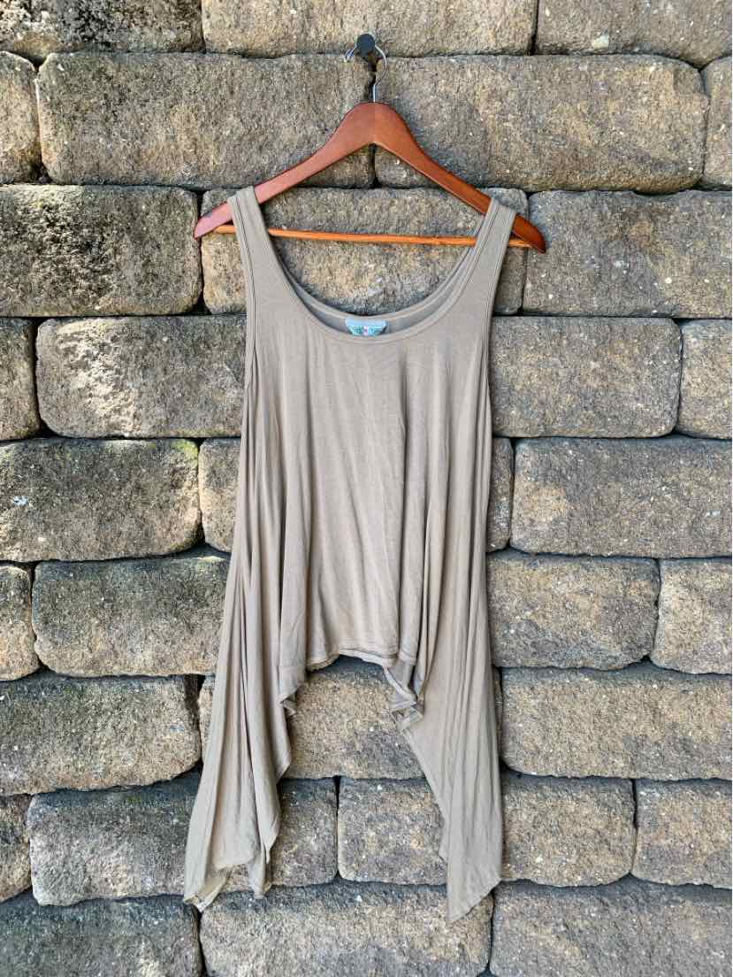 Light taupe sleeveless tank top with draped asymmetrical hem hanging against stone wall.